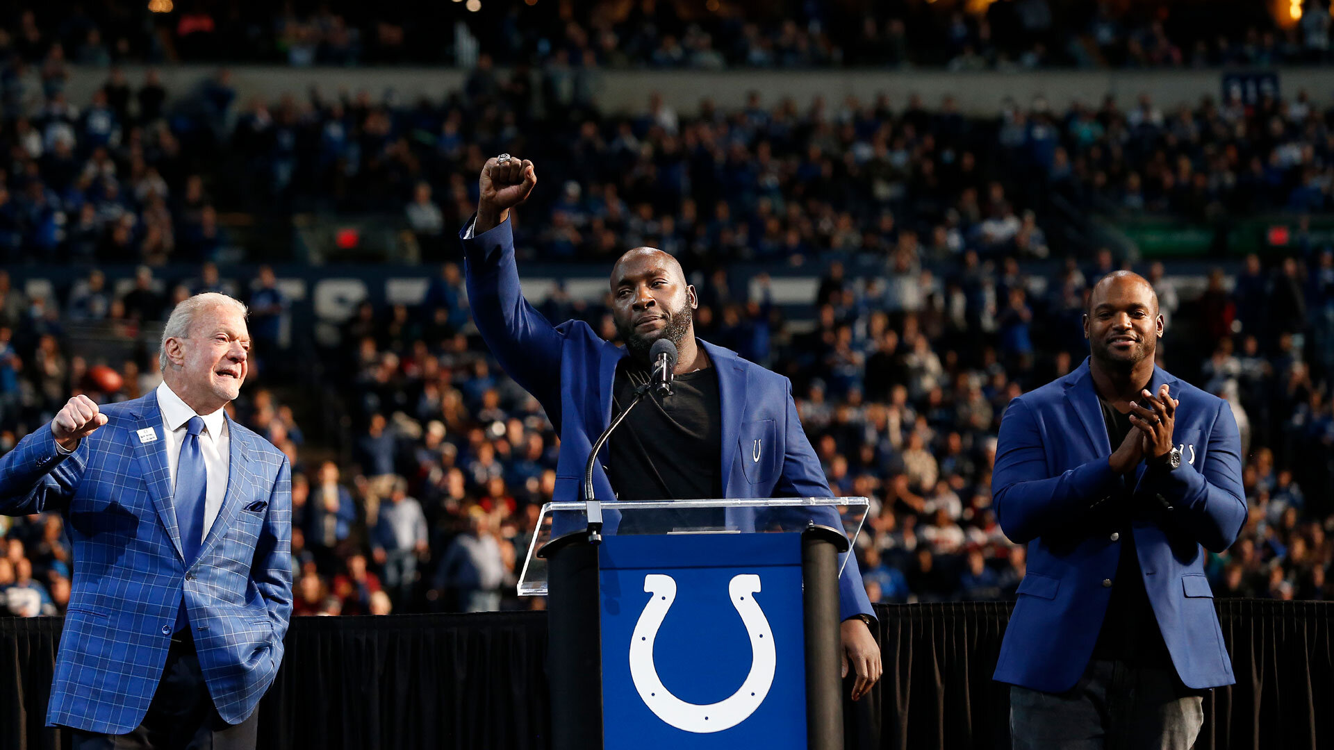 INDIANAPOLIS, IN - NOVEMBER 28: Former Indianapolis Colt Robert Mathis with a fist pump to the crowd as his is inducted into the ring of honor by Indianapolis Colts Owner Jim Irsay and former Indianapolis Colt Dwight Freeney during a NFL game between the Tampa Bay Buccaneers and the Indianapolis Colts on November 28, 2021, at Lucas Oil Stadium in Indianapolis, IN. (Photo by Jeffrey Brown/Icon Sportswire via Getty Images)